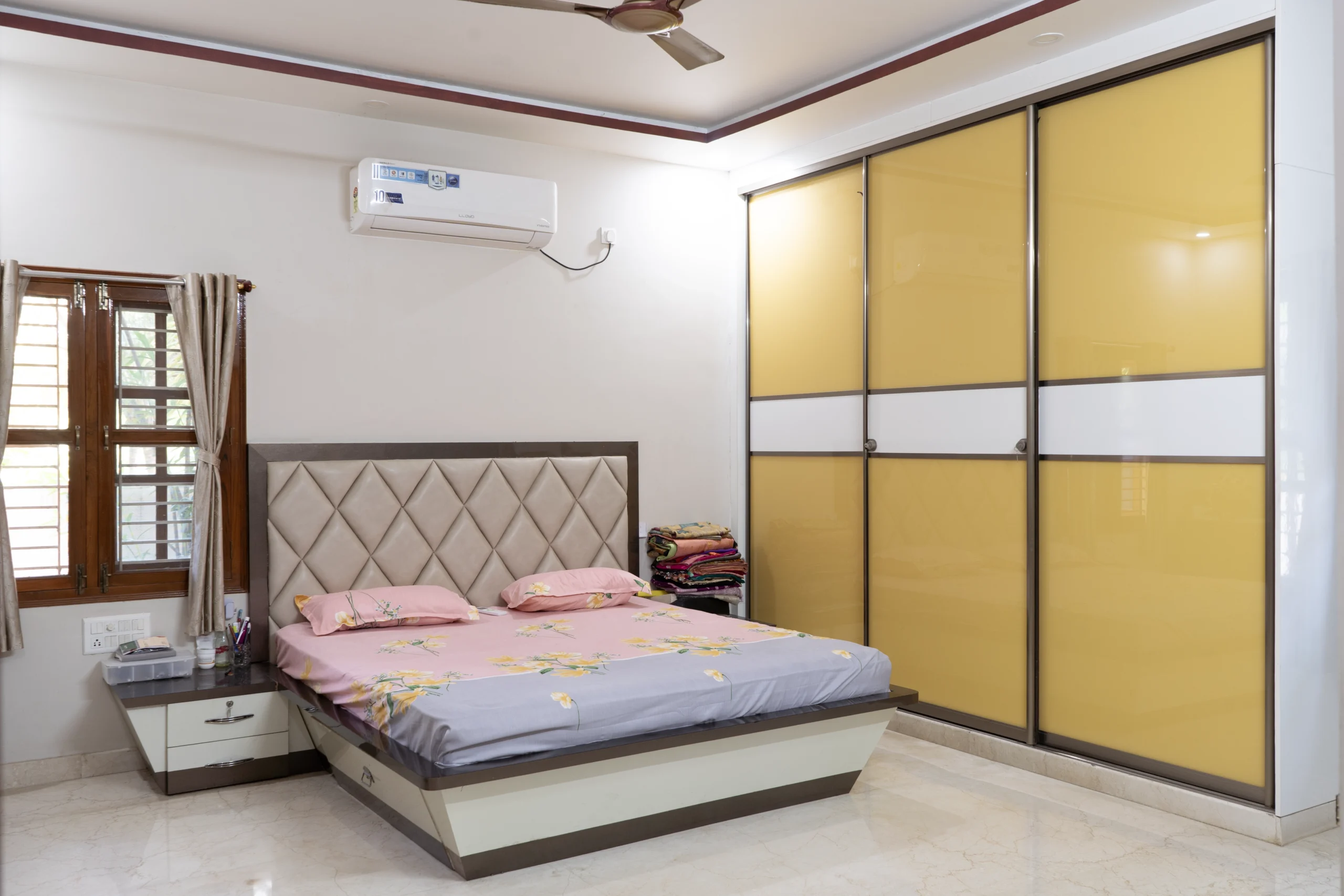 Customized bedroom interior design with wardrobe, wooden flooring, upholstered headboard, and ambient lighting.